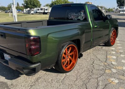 a green truck with orange rims